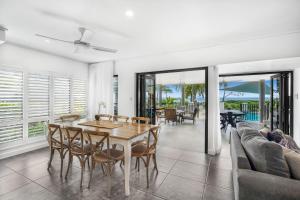 a dining room with a table and chairs and a couch at Belle Escapes Beachfront Luxury Home 53 Arlington Clifton Beach in Palm Cove