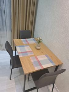 une table en bois avec des chaises et un vase de fleurs. dans l'établissement Apartment in City Centre, à Douchanbé