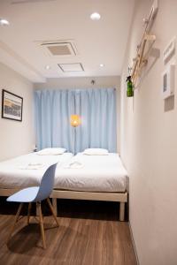 a bedroom with two beds and a chair in front of a window at ELE Hotel Ginza East in Tokyo