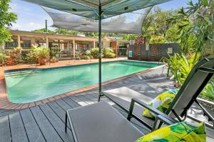 a swimming pool with chairs and an umbrella at Belle Escapes Tropical Haven Holiday Home Palm Cove in Palm Cove