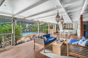 Belle Escapes Tropical Haven Holiday Home Palm Cove في بالم كوف: غرفة معيشة مع أريكة زرقاء وطاولة