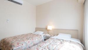 北九州市にあるTabist ホテルテトラ 北九州のベッドルーム1室(ベッド2台、テーブルの上にランプ付)