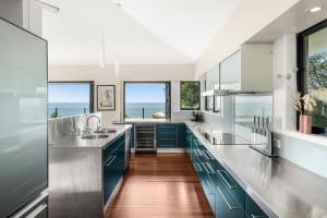 una cocina con encimeras de acero inoxidable y armarios azules en Belle Escapes Trinity Blue Oceanview Home, en Trinity Beach