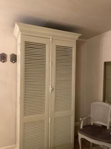 um grande armário branco num quarto com uma cadeira em B&B Silentium em Tielt