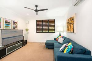 sala de estar con sofá azul y TV de pantalla plana en Belle Escapes Watermark Palm Cove Luxury Home, en Palm Cove