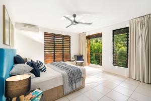 a bedroom with a bed with a ceiling fan at Belle Escapes Watermark Palm Cove Luxury Home in Palm Cove +30 photos