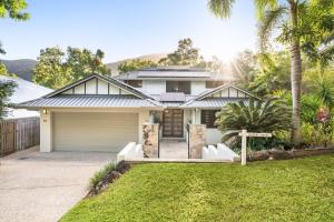 Casa blanca con garaje y palmeras en Belle Escapes Watermark Palm Cove Luxury Home, en Palm Cove
