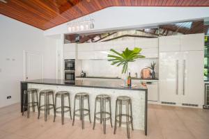 eine Küche mit einer großen Theke mit Hockern in der Unterkunft Belle Escapes 58 Ocean Dr Luxury Home Palm Cove in Palm Cove