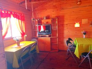 a dining room with a table and a television in a cabin at Cabañas Los Búhos in Tristán Suárez