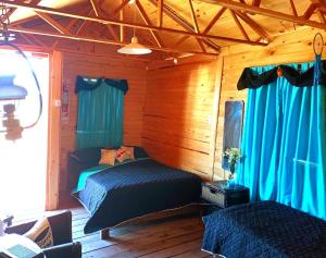 a bedroom with two beds and blue curtains at Cabañas Los Búhos in Tristán Suárez