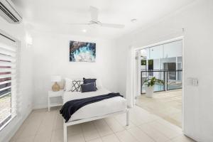 a white bedroom with a bed and a window at Belle Escapes Villa Rosa just minutes to Trinity Beach in Trinity Beach +27 photos