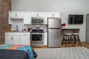 una cocina con armarios blancos y electrodomésticos de acero inoxidable en The Davis Lofts at Main Street - Unit 3D, en Rocky Mount