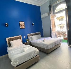 2 camas en una habitación con una pared azul en The Australian Hostel en El Cairo