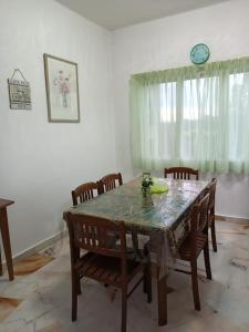 une table à manger avec des chaises et une horloge murale dans l'établissement teluk kemang senorita homestay, à Port Dickson