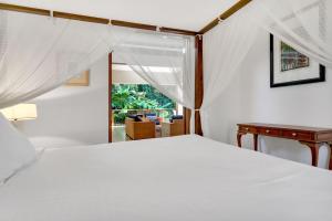 ein Schlafzimmer mit einem Bett und einem Tisch und einem Fenster in der Unterkunft Belle Escapes Luxury Rainforest Villa Palm Cove in Palm Cove + 31 Fotos