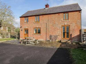 a brick house with a picnic table in front of it at Stables Cottage in Melksham