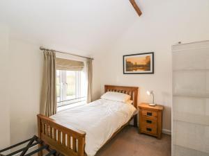 Schlafzimmer mit einem Bett und einem Fenster in der Unterkunft Stables Cottage in Melksham