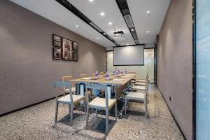 a conference room with a table and chairs and a screen at CM Serviced Apartment Shenzhen Dongmen in Shenzhen