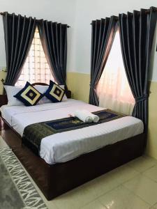 um quarto com uma cama grande e cortinas pretas em Siemreap Nitnit Boutique em Phumĭ Kngan Pông