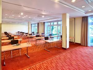 una sala de conferencias con mesas, sillas y ventanas en MAXX by Steigenberger Deidesheim, en Deidesheim