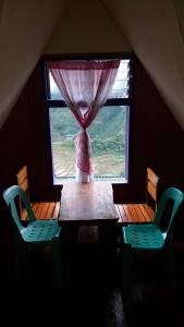 a table and two chairs in a room with a window at Batad Hillside Inn and Restaurant in Banaue