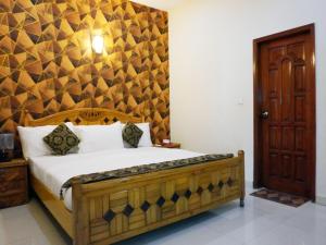 a bedroom with a bed with a wooden headboard at Welcome Guest House in Karachi