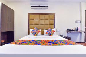 FabHotel Telikos Silver, Near Vadodara Airport في فادودارا: غرفة نوم مع سرير كبير مع بطانية ملونة