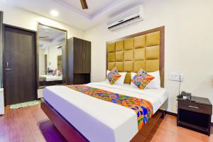 1 dormitorio con 1 cama grande y espejo grande en FabHotel Telikos Silver, Near Vadodara Airport, en Vadodara