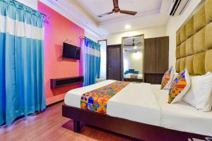 a bedroom with a large bed with colorful curtains at FabHotel Telikos Silver, Near Vadodara Airport in Vadodara