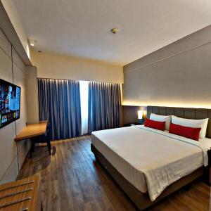 Habitación de hotel con cama grande y TV en Grand Zuri Pekanbaru, en Pekanbaru