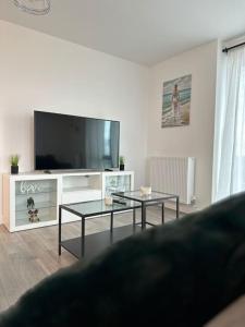 un soggiorno con 2 tavoli e una TV a schermo piatto di NEW Modern 2 Bedroom Apartment! a Dagenham