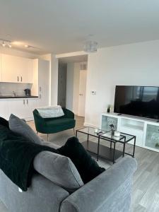 a living room with a couch and a flat screen tv at NEW Modern 2 Bedroom Apartment! in Dagenham