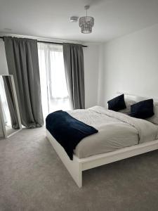 a white bedroom with a large bed in front of a window at NEW Modern 2 Bedroom Apartment! in Dagenham