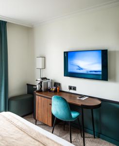 Habitación de hotel con escritorio y TV en la pared en Hotel Paris Boulogne, en Boulogne-Billancourt