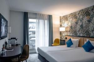 a hotel room with two beds and a desk and a window at Hotel Paris Boulogne in Boulogne-Billancourt