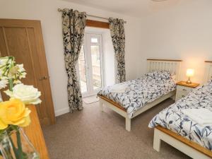 a bedroom with two beds and a window at Dairy Cottage in Newport