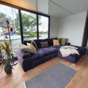 a purple couch in a living room with a large window at Modern, brand new houseboat near Amsterdam in Monnickendam