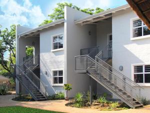 a white house with stairs on the side of it at Apartments @ 125 in Gaborone
