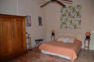 een slaapkamer met een bed en een plafondventilator bij La Paillère chambres d hôtes in Mus