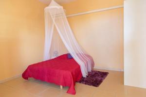 a bedroom with a red bed with a canopy at Studio Colibri... Cap sur le Nord ! in Marigot