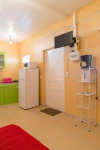 a kitchen with a refrigerator and a tv on the wall at Studio Colibri... Cap sur le Nord ! in Marigot