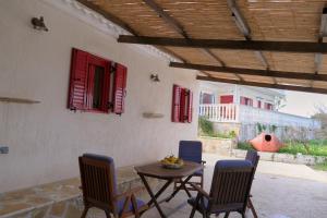 a patio with a table and chairs and red shutters at Yasemia Wood & Stone Villa in Makris Gialos
