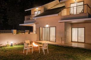 a house with chairs and a fire pit in front of it at StayVista's Enchanting Haven - Modern Interiors, Sprawling Lawn with Gazebo, Swimming Pool, Indoor Games in Panchgani