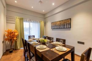 a dining room with a wooden table and chairs at StayVista's Enchanting Haven - Modern Interiors, Sprawling Lawn with Gazebo, Swimming Pool, Indoor Games in Panchgani