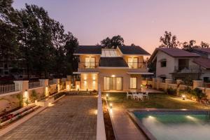 a house with a swimming pool in front of it at StayVista's Enchanting Haven - Modern Interiors, Sprawling Lawn with Gazebo, Swimming Pool, Indoor Games in Panchgani