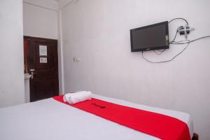 um quarto com uma cama e uma televisão na parede em RedDoorz at H&W Hotel Solo em Surakarta