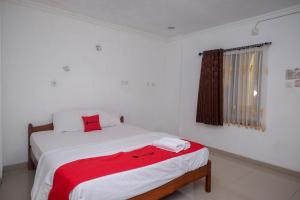 a bedroom with a bed with a red blanket on it at RedDoorz at H&W Hotel Solo in Solo