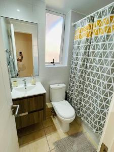 a bathroom with a toilet and a sink and a mirror at Bello departamento Resort vista al mar in Iquique