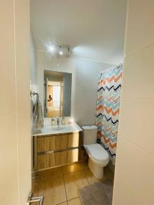 a bathroom with a toilet and a sink and a mirror at Bello departamento Resort vista al mar in Iquique