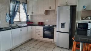 una cucina con armadietti bianchi e frigorifero bianco di Dumela Margate Flat No 30 a Margate